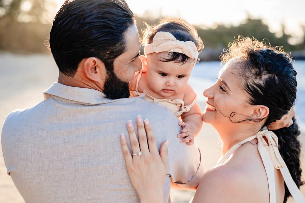 Andy and Tanya facing away from the camera and smiling while the baby is looking towards the camera. 