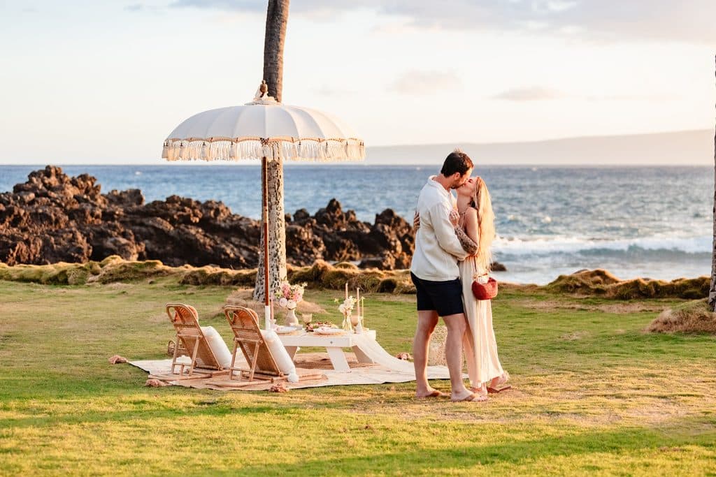 Rachel and Patrick sharing a kiss after the proposal. The occean waves in the background.
