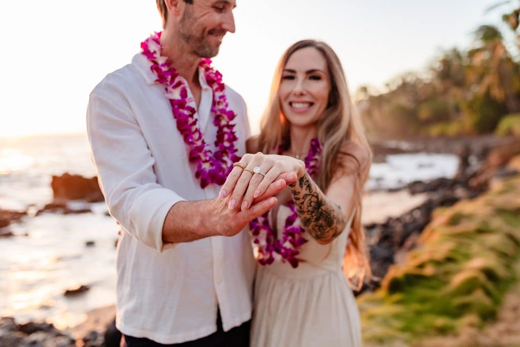 A closer up shot of Rachel showing off her ring while Patrick holds her hand up. Their smiling in the background.