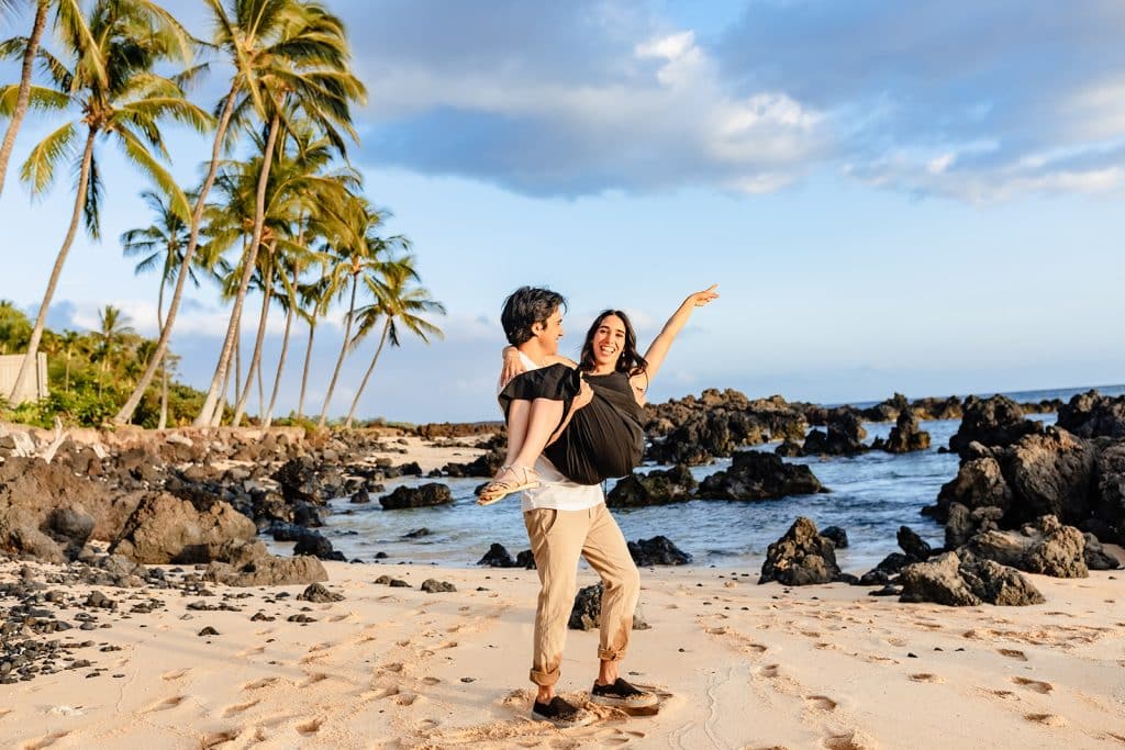Hector holding Alejandra while she smiles at the camera and strikes a pose with her arm up.