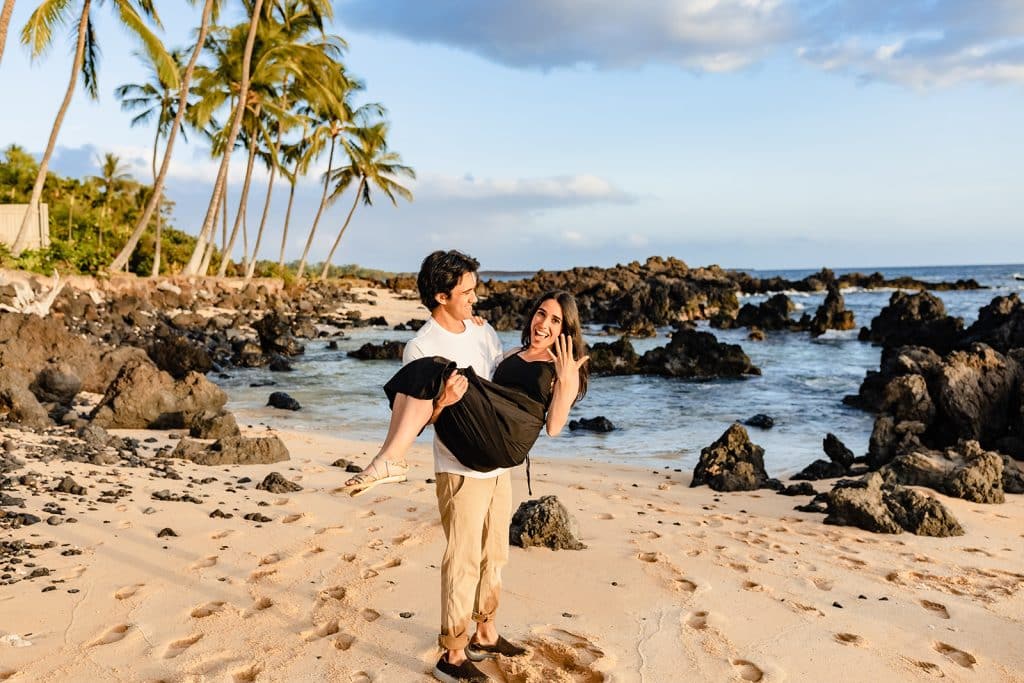 Hector holding Alejandra while she smiles at the camera and strikes a pose showing her ring off.