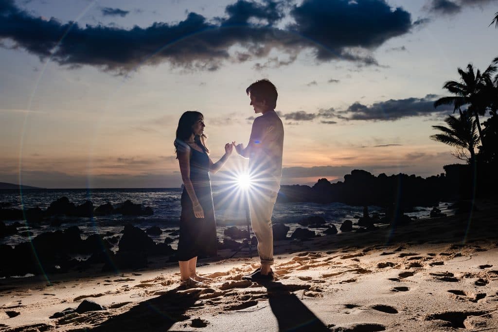 Hector and Alejandra standing with the sunsetting behind them. A light burst in between them, and they are doing a pinky promise to each other.