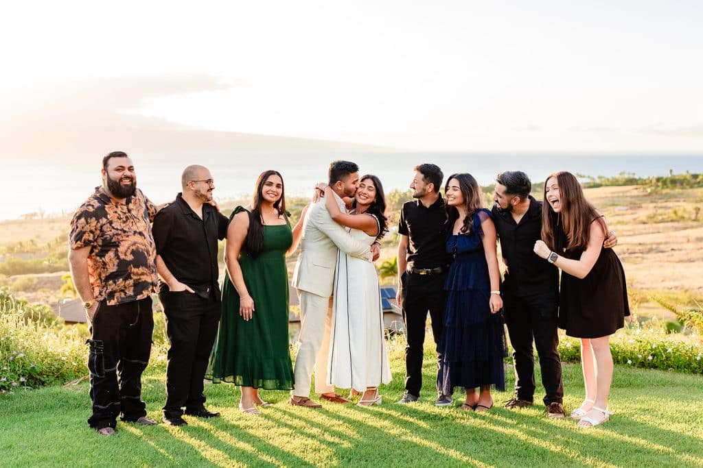 A group photo of all of the family and friends smiling and laughing as Pruthvi gives Tithi a kiss on the cheek
