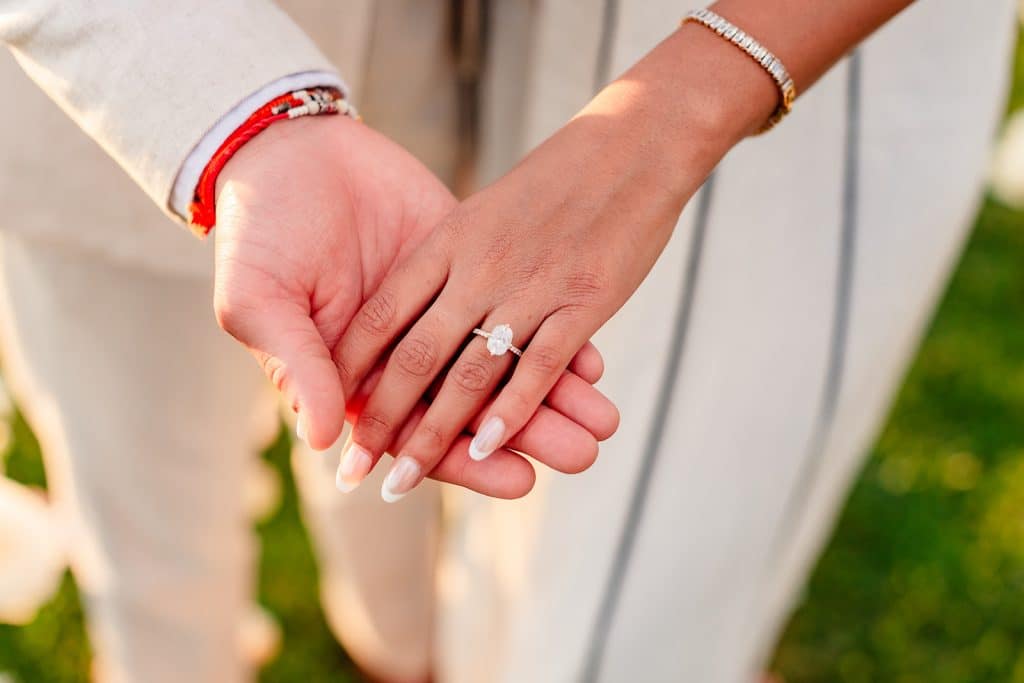 A close up photo of Tithi and Pruthvi's hands to showcase her solitaire oval engagement ring.