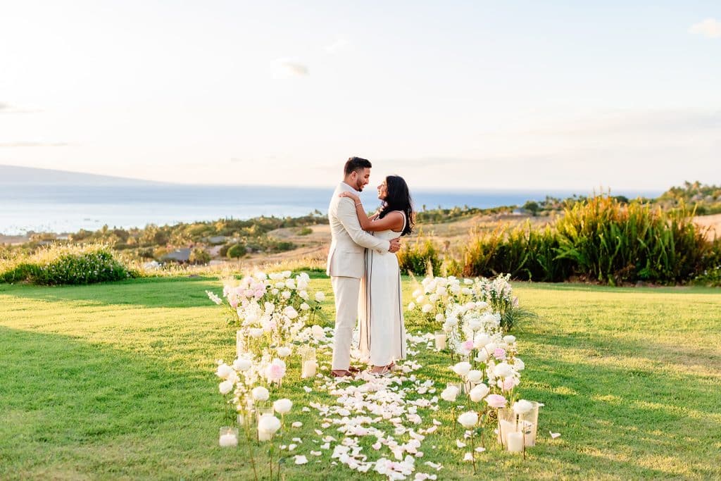 Pruthvi and Tithi embracing and facing each other while standing among the flowers as the sun sets.
