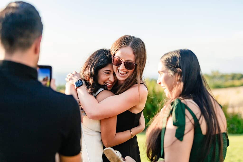 Tithi hugging one of her friends as others are taking photos and videos on their phones.