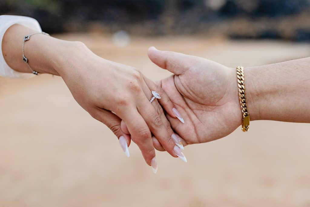A close up photo of Brandon holding Alexis' hand so the ring is in full view.