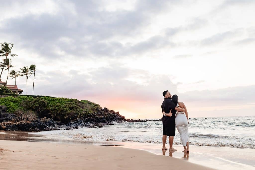 Brandon and Alexis holding each others wasit and looking off into the sunset as the sun goes down.