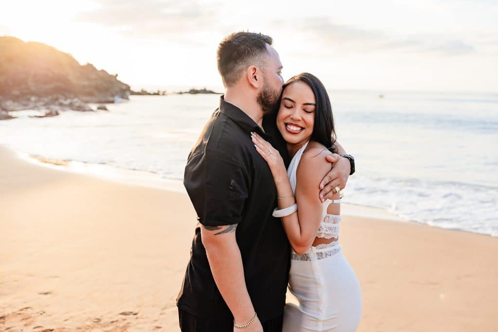 Brandon and Alexis hugging while he kisses her temple and she rests her hand on his chest. 