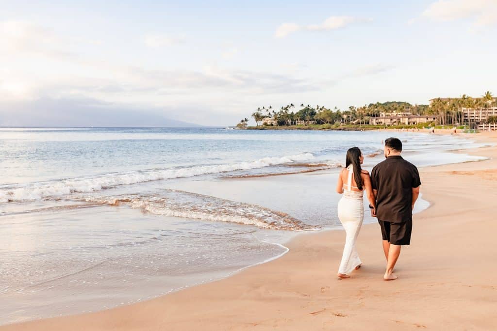 Brandon and Alexis holding hands and walking the shore of the beach 