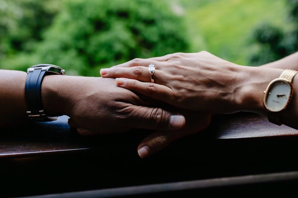 A close up of Raynell and Denise's hands. Denise's engagement ring is the main focus.