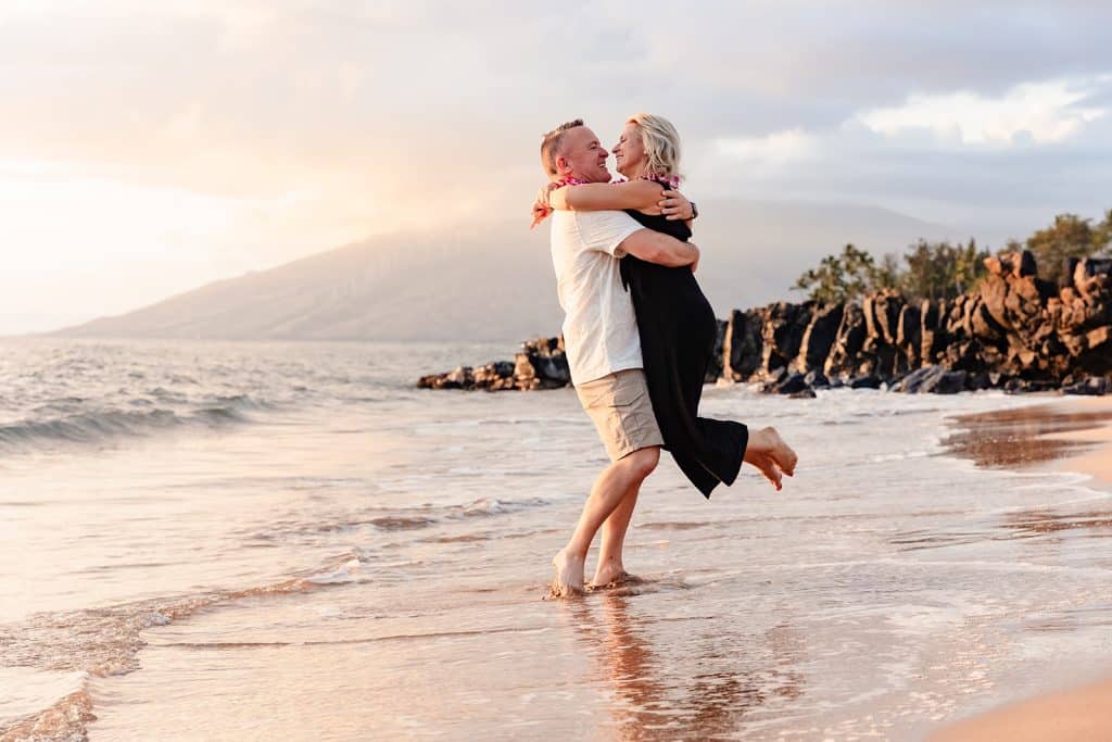 Andy picking up Joy on the coast and spinning her around while his feet are in the water.