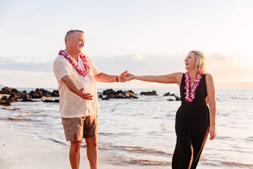 Andy holding out his arms to Joy as she grabs one hand and pulls him along the shore.
