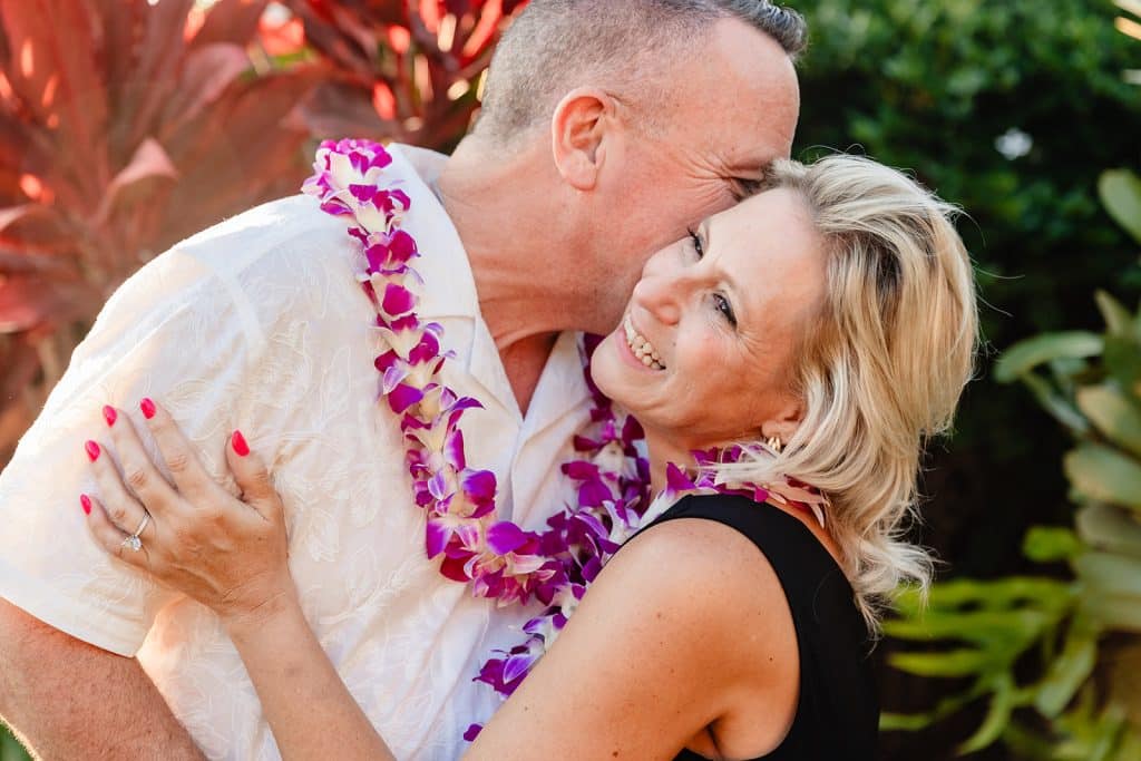 A close up of Andy giving Joy a kiss in the cheek as she holds onto him and laughs.