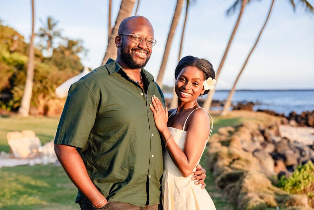 Ernest and Gloria standing together and smiling for the camera. Ernest is holding her waist as she rests her hand on his chest. The glow of the sunset shining on their faces.